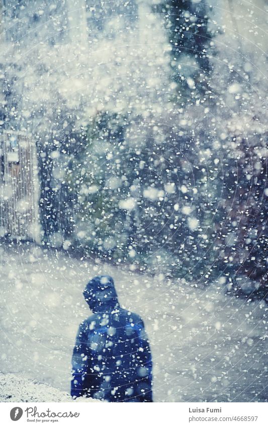 Eine Person mit Windjacke geht unter starkem Schneefall mit großen Schneeflocken Mann Spaziergang Winter Straße Natur Schneesturm große Schneeflocken Muster