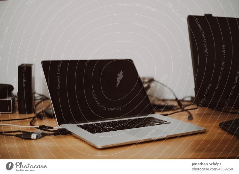 Laptop auf Holztisch neben externen Monitor und Festplatten mit Kabelsalat Innenaufnahme zuhause selbstständig Arbeit & Erwerbstätigkeit Job Heimarbeitsplatz