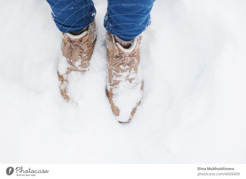 Winter beige Schuhe oder Stiefel in den tiefen Schnee im Winter Park während des Spaziergangs Nahaufnahme. Frau in Jeans und Hipster Schuhe zu Fuß im Winter Wald im Schnee.