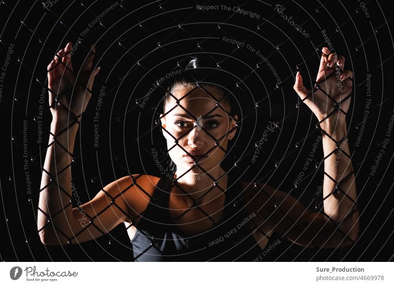 Die Idee der Überwindung von psychischen und physischen Barrieren und Hindernissen Junge sportliche Frau schaut dich durch das Netz an Erwachsener Hand Person