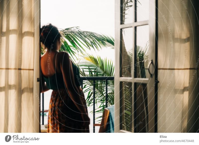 Frau steht in geöffneter Balkontür und blickt auf Palmen Urlaub Unterkunft Ferien & Urlaub & Reisen offen Ausblick exotisch entspannt Sonnenschein Außenaufnahme