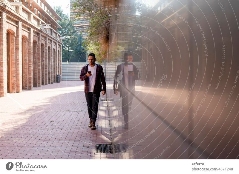 Junger Mann geht im Freien spazieren und benutzt dabei sein Smartphone laufen Person Technik & Technologie Erwachsener Großstadt Mitteilung Lifestyle Handy