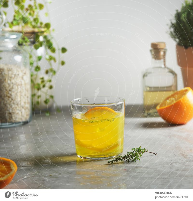 Selbstgemachte Orangenlimonade mit Thymian am grauen Betonküchentisch selbstgemacht orange Limonade Küche Tisch Hälfte Glas Hafer Flasche vorbereitend