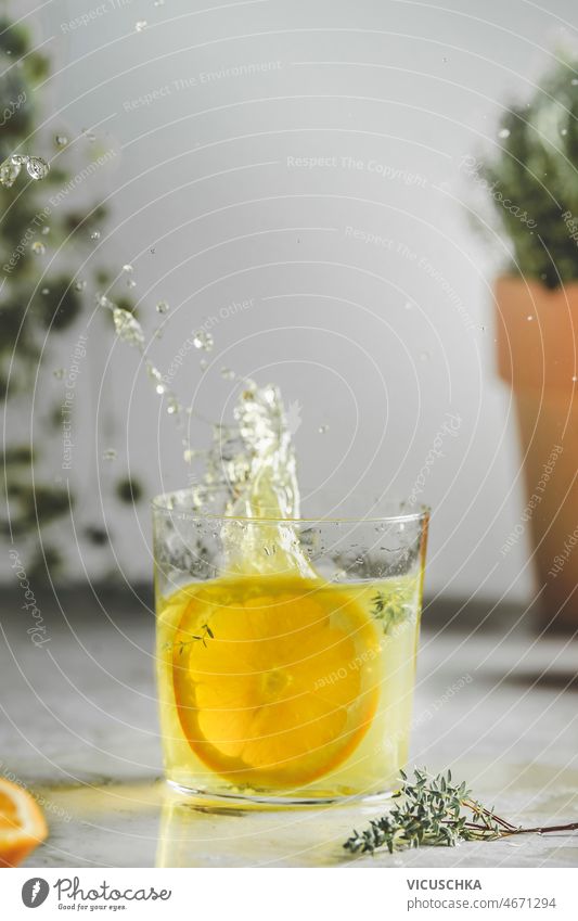 Hausgemachte spritzende Orangenlimonade im Glas mit Thymian auf dem Küchentisch selbstgemacht Geplätscher orange Limonade Tisch Wand Pflanze Hintergrund
