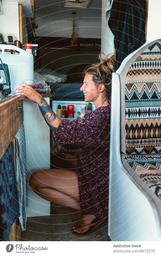 Lächelnde Frau holt Lebensmittel aus dem Kühlschrank im Lieferwagen Reisender Wohnwagen Anhänger pflücken vorbereiten reisen Urlaub Wohnmobil Tourismus Fernweh
