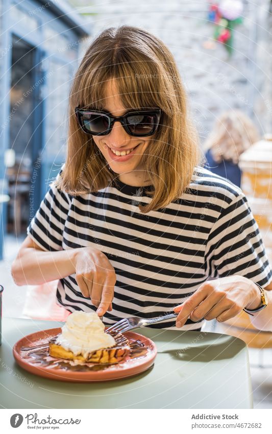 Fröhliche Frau isst Dessert auf der Terrasse eines Cafés Waffel Speiseeis süß essen Feinschmecker Leckerbissen lecker geschmackvoll Lebensmittel Geschmack