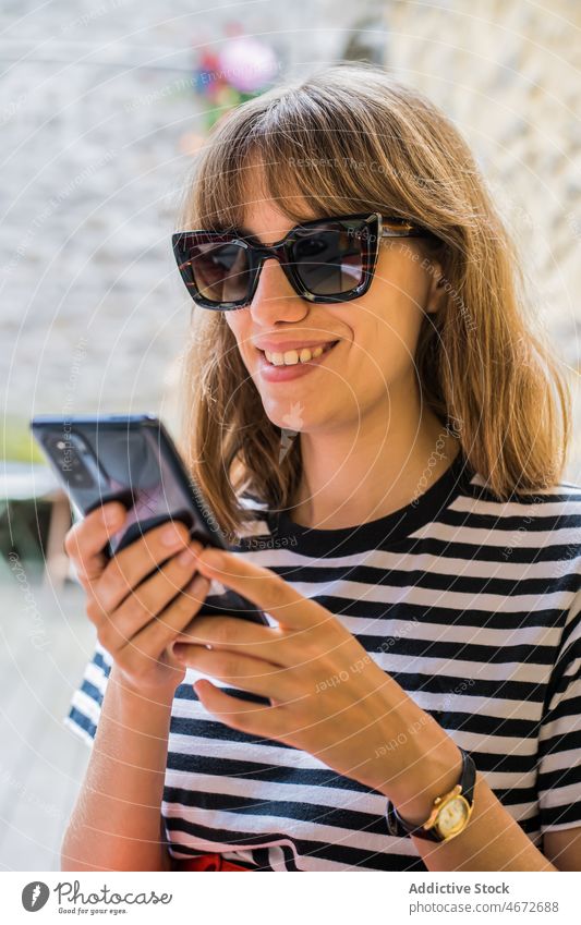 Frau surft auf der Terrasse eines Cafés auf ihrem Smartphone Browsen Textnachricht Lächeln online Straße Kaffee Talkrunde Frankreich Internet Glück Surfen