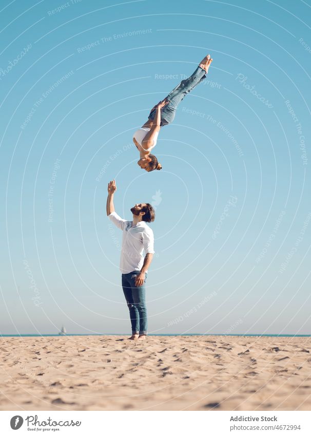 Frau macht Purzelbaum über Mann am Strand Paar Überschlag Trick Sport Stunt Artist akrobatisch Übung Stauanlage üben Hafengebiet Gleichgewicht passen Figur
