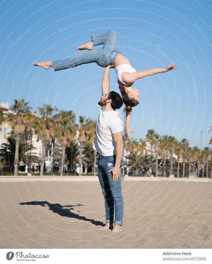 Mann hält Frau auf ausgestrecktem Arm am Strand Paar Sport Artist akrobatisch Übung Stauanlage üben Hafengebiet sportlich beweglich passen Figur Küste Ufer