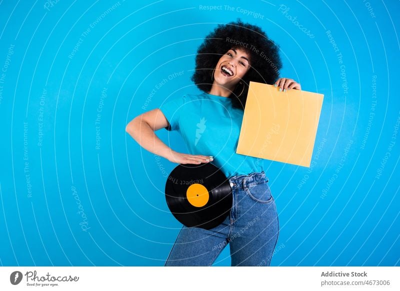 Positive hispanische Frau mit alter Schallplatte Afro-Look Vinyl Aufzeichnen retro altehrwürdig Lächeln Nostalgie altmodisch meloman ethnisch Glück Verpackung