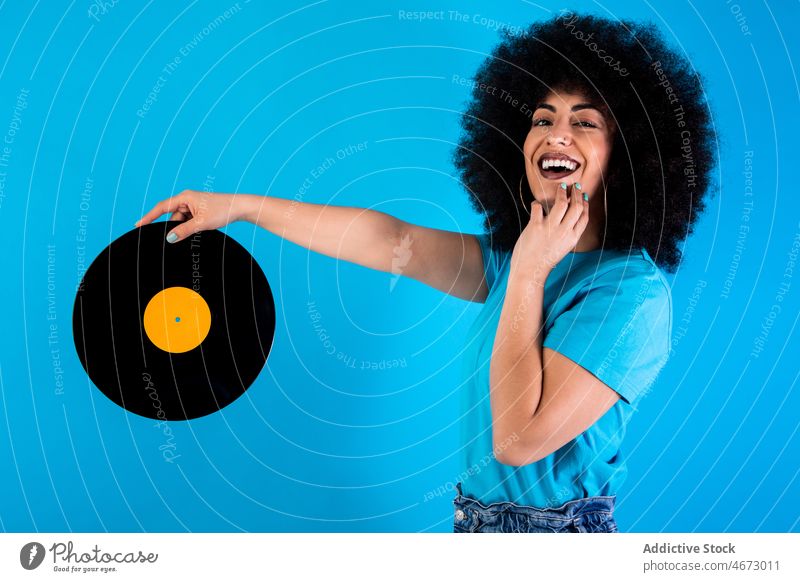Positive hispanische Frau mit alter Schallplatte Afro-Look Vinyl Aufzeichnen retro altehrwürdig Lächeln Nostalgie altmodisch meloman ethnisch Glück Stil