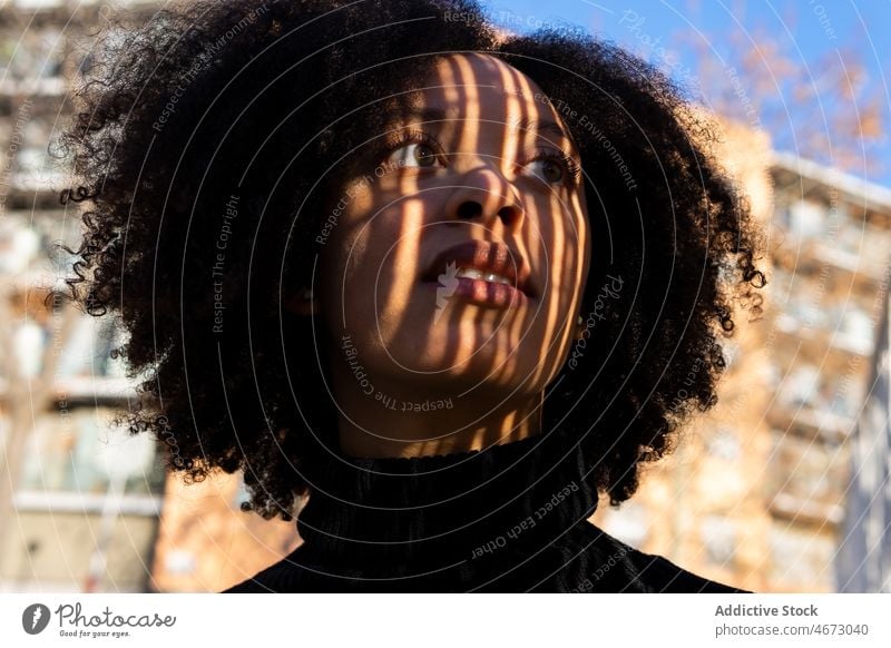Charmante schwarze Frau auf der Straße feminin Vorschein Großstadt Stil urban krause Haare Frisur brünett charmant Afroamerikaner Dame Sonnenlicht dunkles Haar