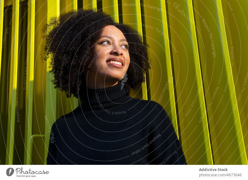 Fröhliche schwarze Frau in der Nähe der grünen Wand Straße Stil Großstadt feminin Vorschein Konstruktion Lächeln Gebäude Mode Afroamerikaner Dame Stadt Design