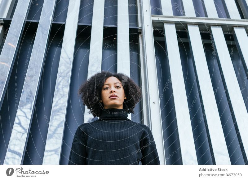 Emotionslose schwarze Frau an der Wand Straße Stil Großstadt feminin Vorschein Konstruktion Gebäude Mode ethnisch Afroamerikaner Dame Stadt Design charmant