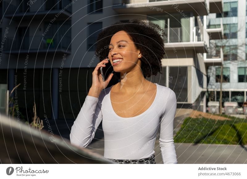 Erfreute schwarze Frau, die auf der Straße telefoniert Telefonanruf Gespräch diskutieren Talkrunde Stil urban Großstadt Kommunizieren Smartphone Funktelefon