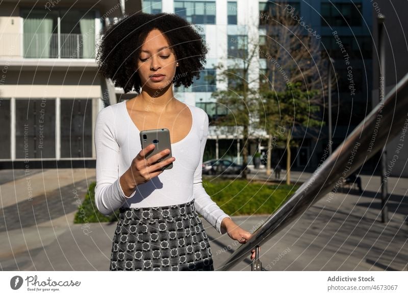 Schwarze Frau, die auf der Straße eine Textnachricht auf einem Mobiltelefon schreibt Talkrunde Browsen ethnisch Stil urban Großstadt Gerät Smartphone