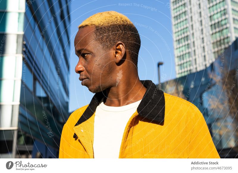 Schwarzer Mann in der Nähe eines Hochhauses Stil trendy Gebäude urban Streetstyle Straße Vorschein Großstadt mehrstöckig gefärbtes Haar modern jung lässig