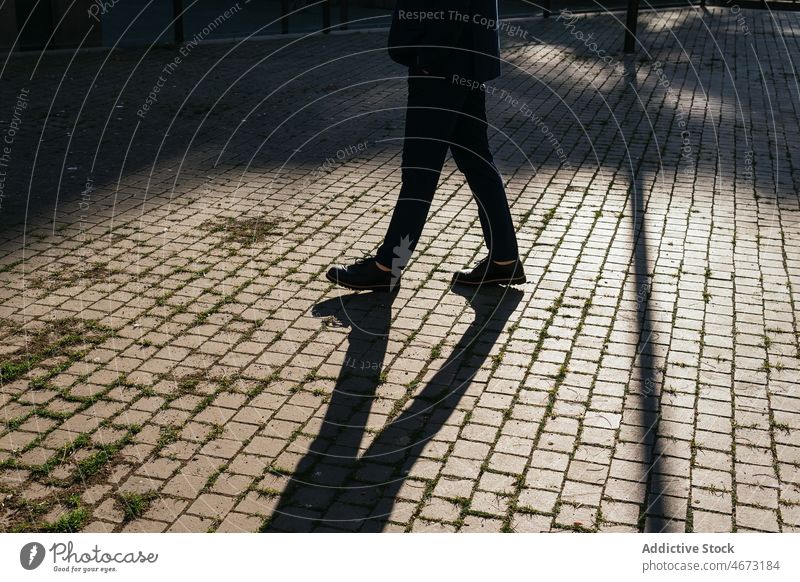 Unbekannter Mann geht auf dem Bürgersteig Straßenbelag Großstadt Sonnenlicht Laufsteg Spazierweg urban Weg Schatten Oberbekleidung Sonnenschein Stadt schlendern