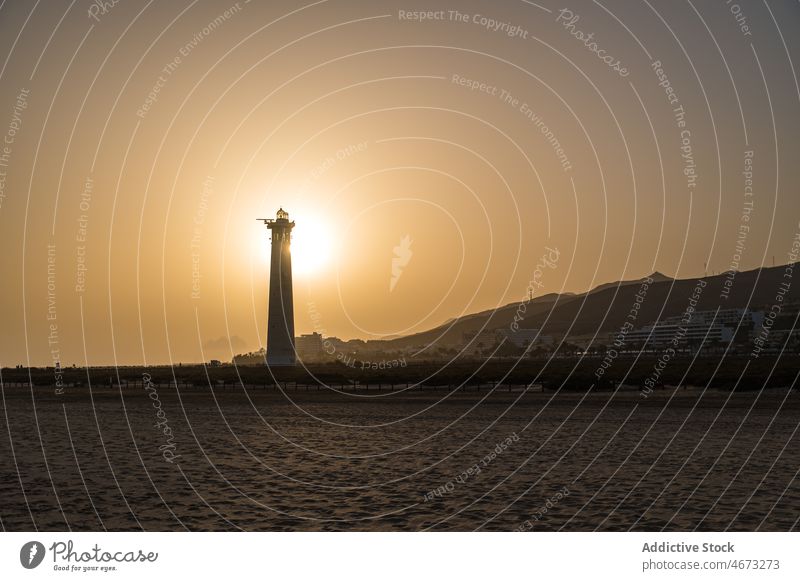 Leuchtturm im Sonnenuntergangslicht am Meeresufer Leuchtfeuer Abend Turm Sommer Strand Küste Sonnenlicht Silhouette Landschaft ruhig Windstille friedlich