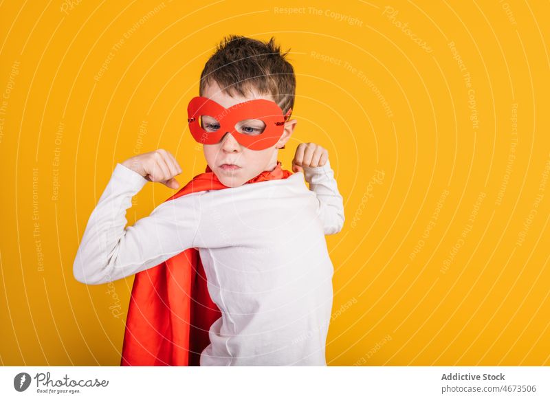 Junge im Superhelden-Outfit zeigt Muskeln Kind Erfolg Sieg erreichen Gewinner Tracht Atelier Porträt Mut Kraft Ehrgeiz Mundschutz Bizeps Held selbstbewusst
