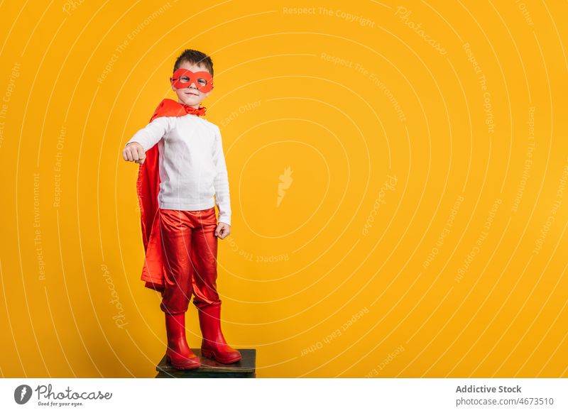 Verspielter Junge in Superhelden-Uniform, der so tut, als würde er fliegen Kind Mundschutz Flug Fliege die Faust ballen Tracht Porträt Atelier Kraft Mut Held