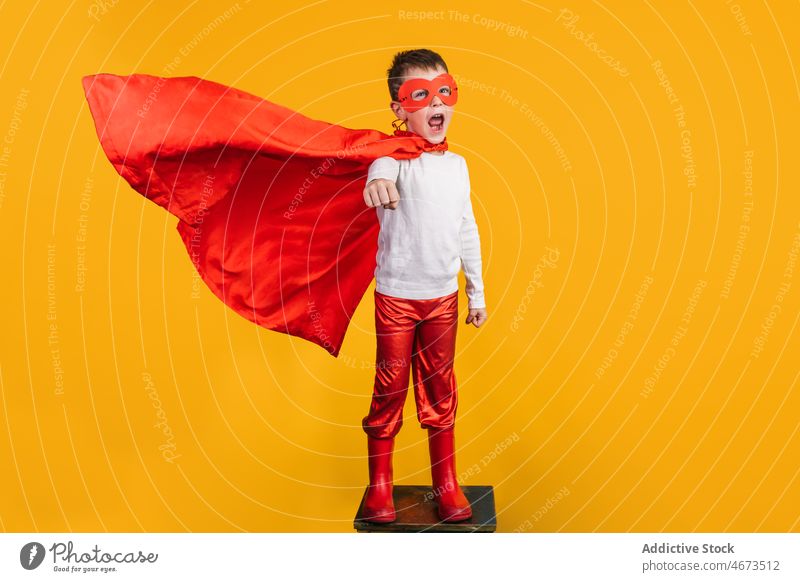 Junge in Superheldenuniform, der so tut, als würde er fliegen Kind Mundschutz Flug Fliege die Faust ballen Tracht Porträt Atelier Kraft Mut Held selbstbewusst