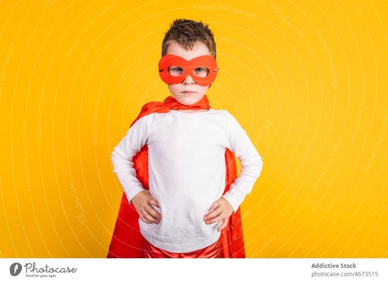Selbstbewusstes Superheldenkind denkt im Studio Junge Kind Tracht Mut Kraft Ehrgeiz Porträt Atelier Mundschutz Hand auf der Taille Held selbstbewusst Kap