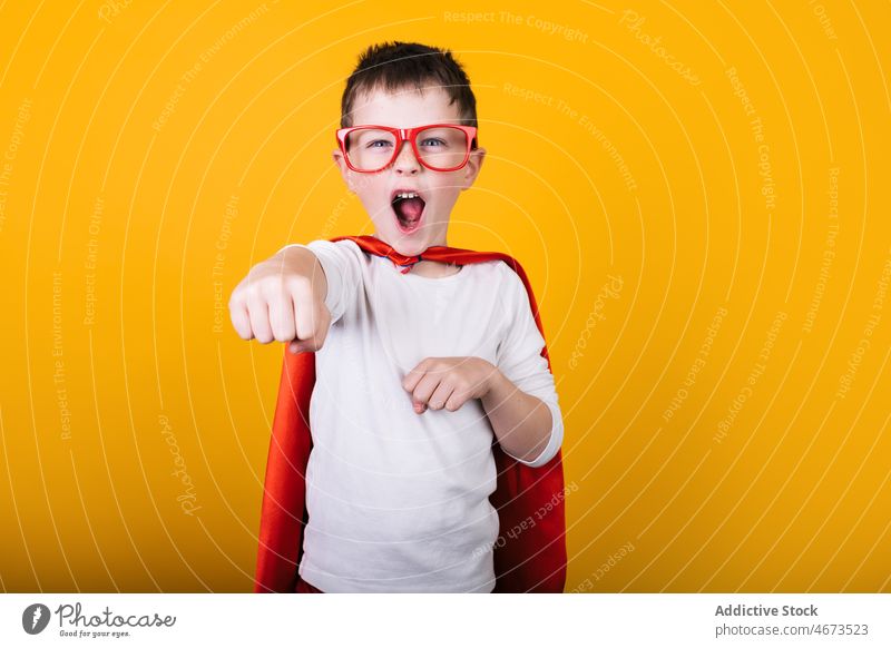Verspielter Junge in Superhelden-Uniform, der so tut, als würde er fliegen Kind Flug Fliege die Faust ballen schreien Tracht Porträt Atelier Kraft Mut Held