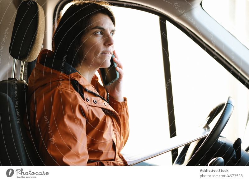 Frau spricht im Lkw mit Smartphone Fahrer Telefonanruf Gespräch diskutieren Lastwagen Verkehr Arbeit logistisch Schriftstück verteilen professionell Job