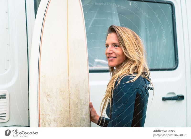Glückliche Frau mit Surfbrett in der Nähe des fahrenden Transporters Surfer Neoprenanzug heiter Lächeln Badeanzug bereit Surfen Sommer Natur Hobby positiv