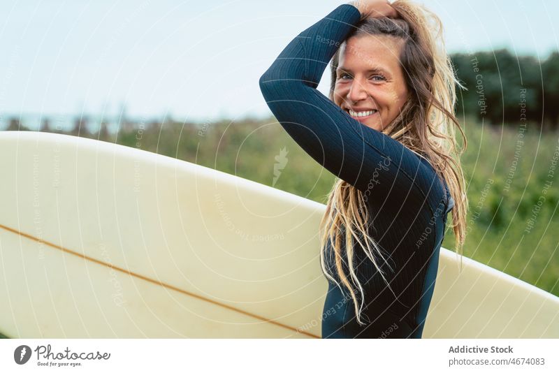 Blonde Frau im Neoprenanzug mit Surfbrett unterwegs Surfer stehen Spaziergang bereit Sommer Badeanzug Urlaub Porträt Natur Feiertag Hobby sportlich