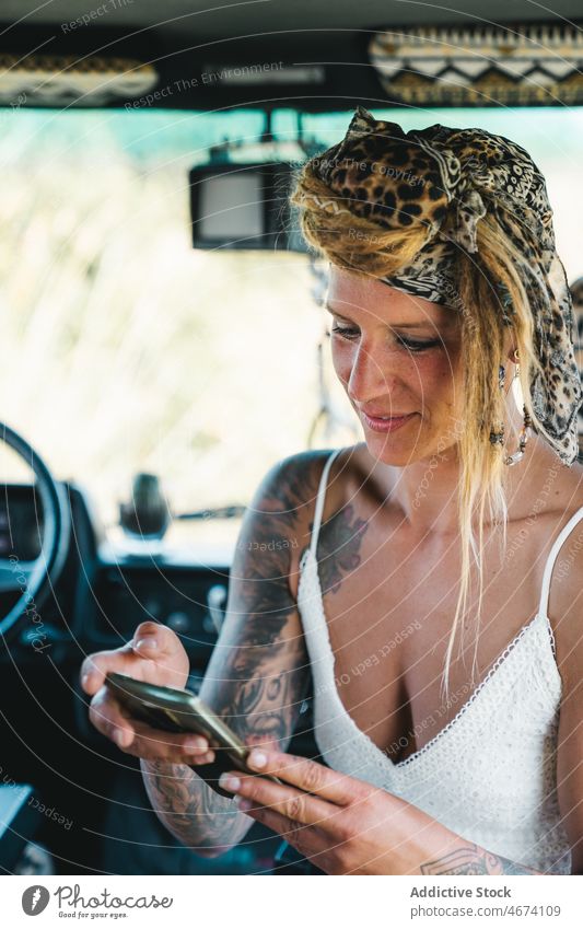 Positive Frau, die in einem Lieferwagen eine SMS auf ihrem Smartphone schreibt Reisender benutzend Laptop Wohnmobil Browsen Autoreise rv Kleintransporter