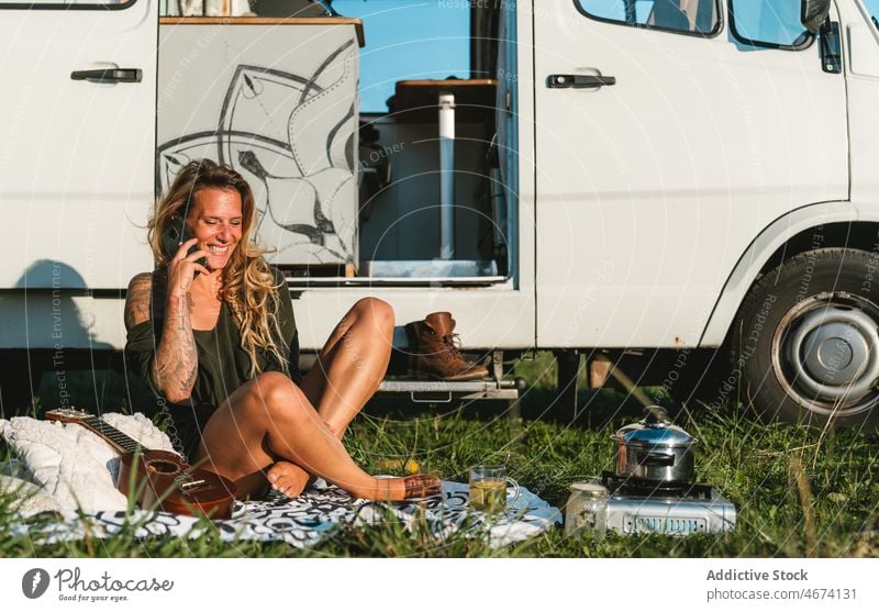Frau spricht in der Nähe eines Campingwagens mit ihrem Smartphone Telefonanruf Gespräch sprechen Talkrunde Lächeln Hipster Reisender Wohnmobil Kleintransporter