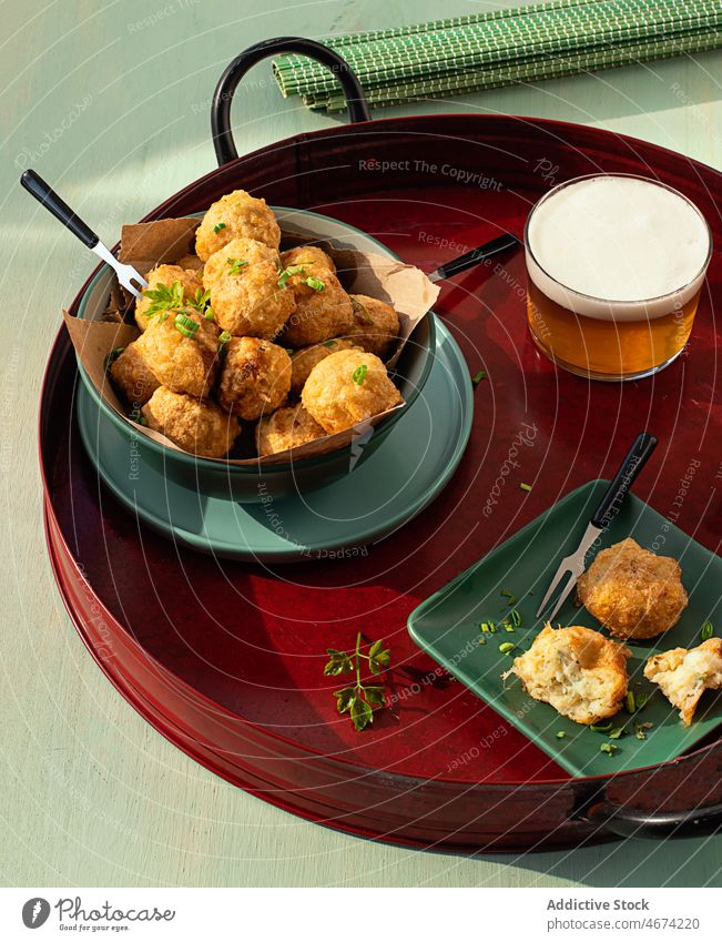 Kabeljau-Frikadellen auf einem Tablett mit frischen Kräutern und einem Glas Bier Fisch Snack Bälle Lebensmittel Petersilie Fischfrikadelle Bar frittiert Tapa