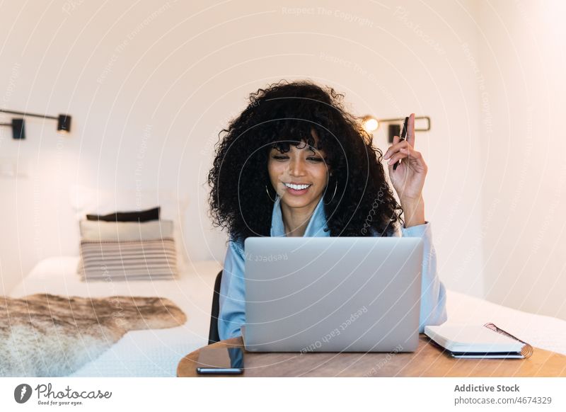 Lächelnde schwarze Frau arbeitet zu Hause am Laptop benutzend Arbeit online Internet Netbook Smartphone Telefon Notebook Afroamerikaner Anschluss freiberuflich