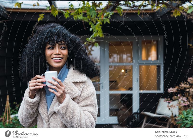 Lächelnde schwarze Frau mit einer Tasse Kaffee trinken sich[Akk] entspannen ruhen Haus heimwärts Kälte Kaffeepause warm afroamerikanische Frau Becher