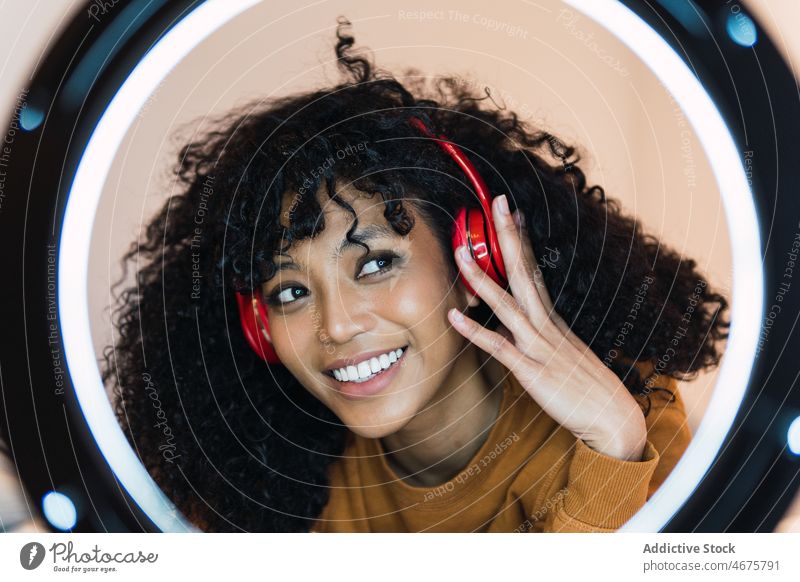 Lächelnde schwarze Frau, die mit Kopfhörern Musik hört benutzend zuhören Ringlampe meloman sich[Akk] entspannen Kälte ruhen afroamerikanische Frau jung heiter