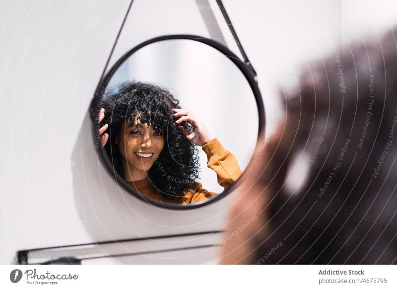 Lächelnde schwarze Frau vor dem Spiegel zu Hause Reflexion & Spiegelung wach Morgen Vorschein Schönheit Routine feminin perfekt Afroamerikaner krause Haare jung