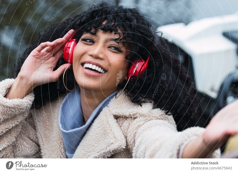Fröhliche schwarze Frau, die mit Kopfhörern Musik hört zuhören benutzend Spaziergang Großstadt Straße urban Wochenende Afroamerikaner sich[Akk] entspannen