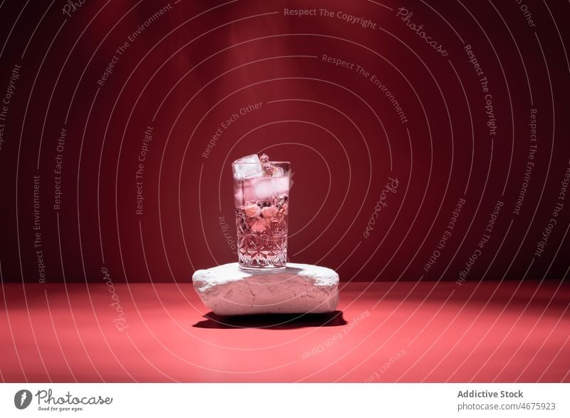 Gin Tonic mit Eis auf rotem Hintergrund Cocktail rosa Alkohol Getränk Schnaps Glas Aperitif Atelier kalt Würfel trinken Erfrischung gefroren liquide Bestandteil