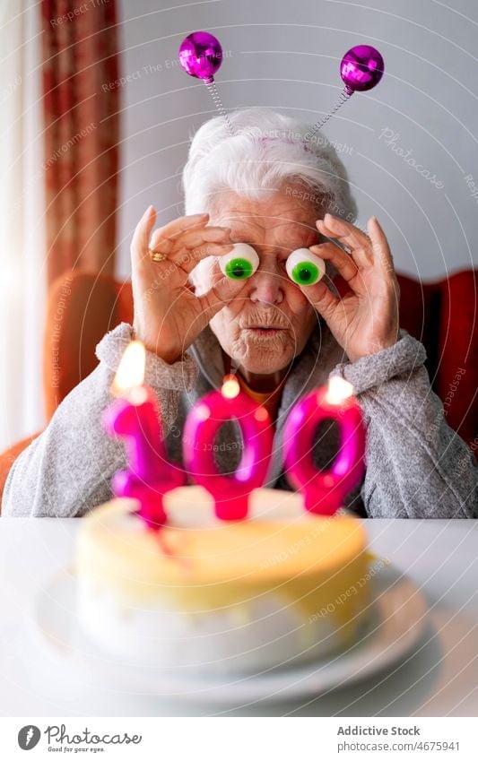 Lustige ältere Frau, die ihren 100. Geburtstag zu Hause feiert feiern Senior Spaß haben Party heimwärts Kuchen Kerze gealtert Hundertste hundert Feiertag süß
