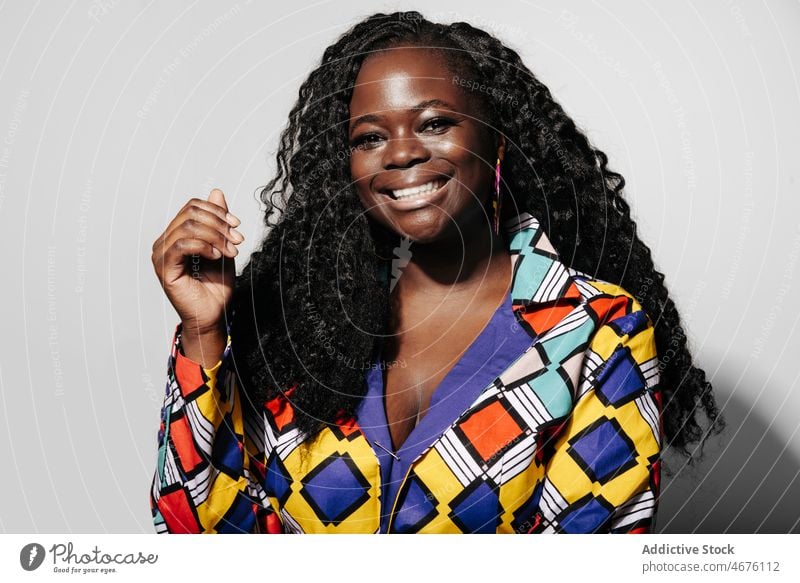 Fröhliche schwarze Frau schaut in die Kamera kurvenreich Afroamerikaner ethnisch Stil trendy krause Haare Glück heiter Afro-Look Mode Lächeln Frisur farbenfroh