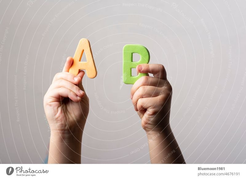 Die Hände halten zwei schwammige Buchstaben des Alphabets AB Briefe Hintergrund vereinzelt Klotz Kapital Fall Zusammenarbeit neben Konzept Niveau mischen Orden