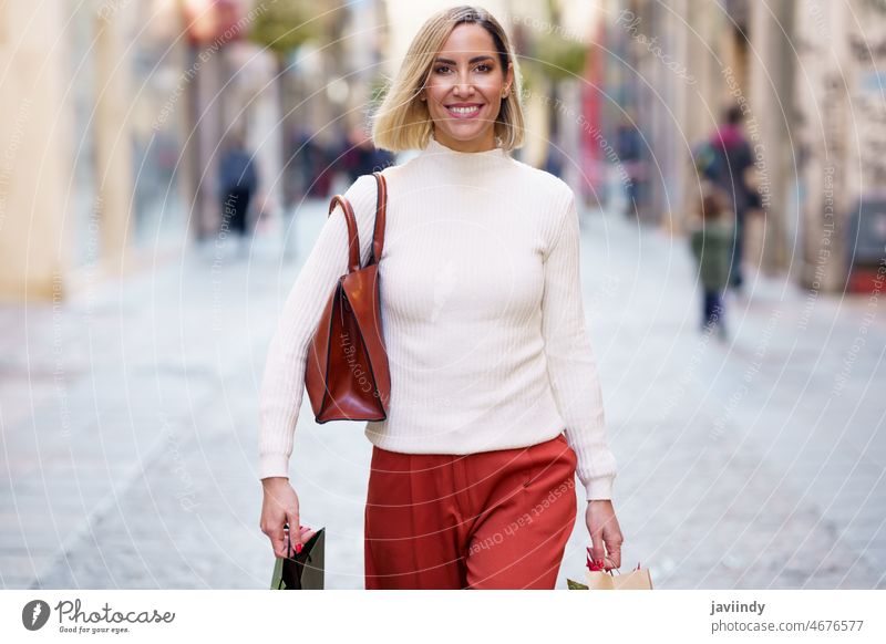 Lächelnde Frau mit Einkaufstaschen auf der Straße Käufer führen sorgenfrei Konsumverhalten Ware Einzelhandel modern Kauf Glück Tüte positiv froh Großstadt
