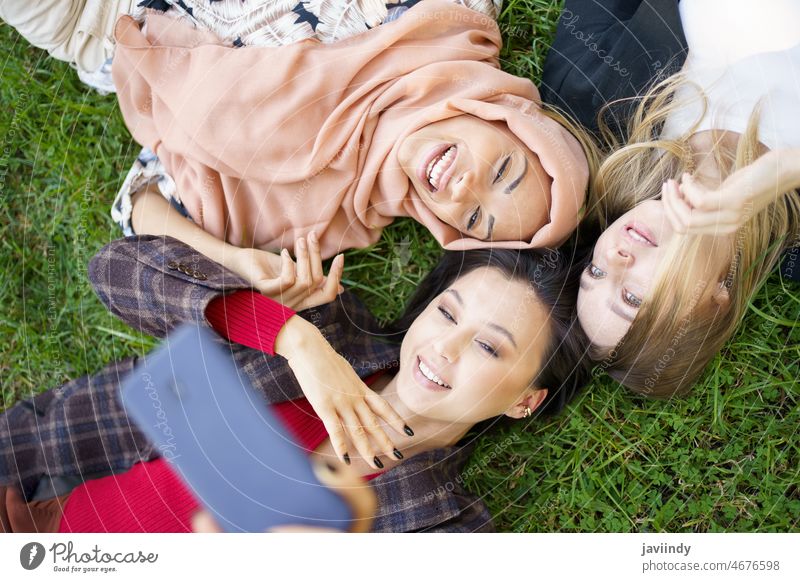 Gemischtrassige Frauen machen zusammen ein Selfie im Park Freund Freundschaft Selbstportrait Rasen Fotografie einfangen Bonden Gedächtnis Smartphone