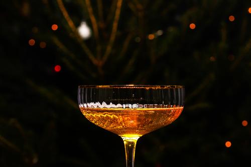 Schöne Glas Champagner gegen Bokeh Lichter Hintergrund mit einem geschmückten Weihnachtsbaum. Frohes neues Jahr 2022. Weihnachten und Neujahr Urlaub Hintergrund, Wintersaison.