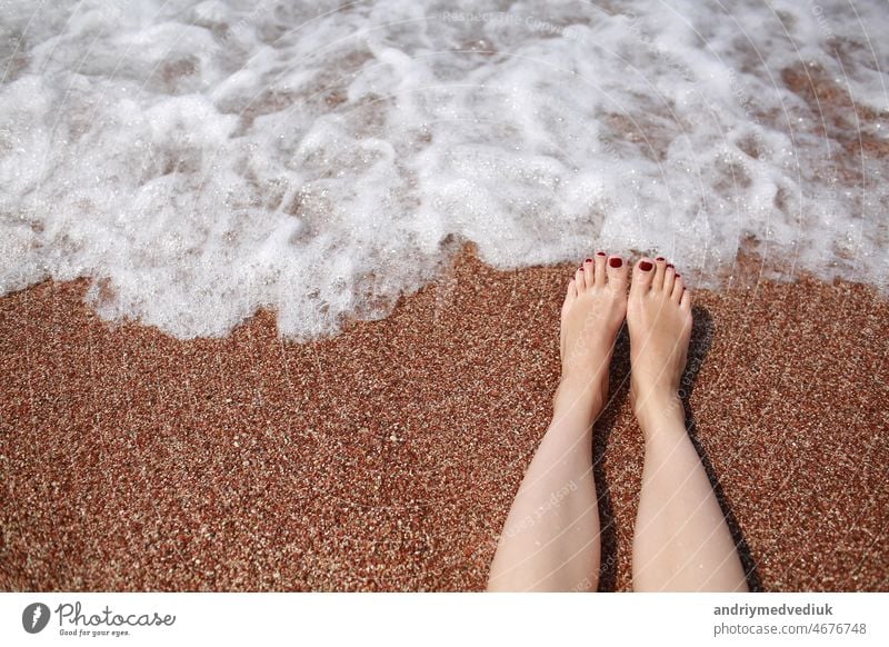 Reise-Konzept - Frau die Beine auf schönen tropischen Strand mit Kieselstein Sand. Füße auf Sand und Welle im Sommer. Mädchen barfuß im Ozean Wasser im Urlaub reisen. Fühlen Sie sich glücklich und entspannen. kopieren Raum.