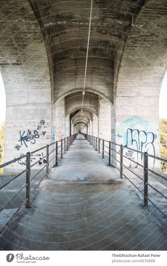 Betonbrücke mit Eisengeländer grafitti Perspektive Brücke Geländer Bögen Mittelpunkt