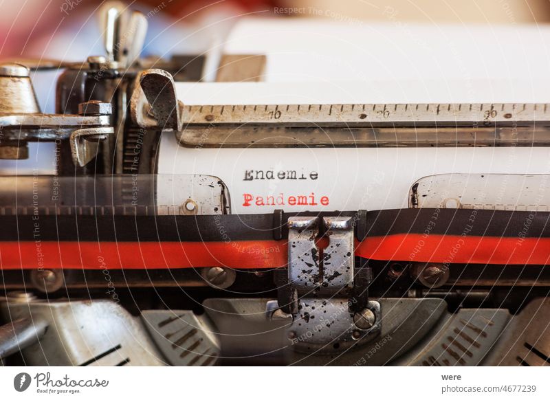 Das deutsche Wort Endemie Pandemie geschrieben mit einer alten mechanischen Schreibmaschine mit roten und schwarzen Farbband in schwarzer und roter Farbe auf einem weißen Blatt Papier