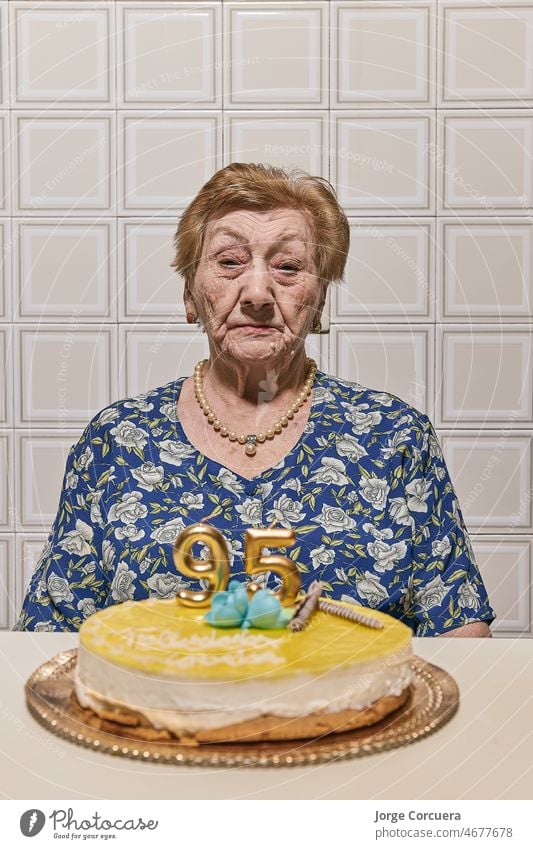 Eine ältere Frau blickt auf eine mit Kerzen bestückte Torte. Blick Ruhestand lässig reif knittern positive Stimmung Liebe heiter Fröhlichkeit Menschen Familie